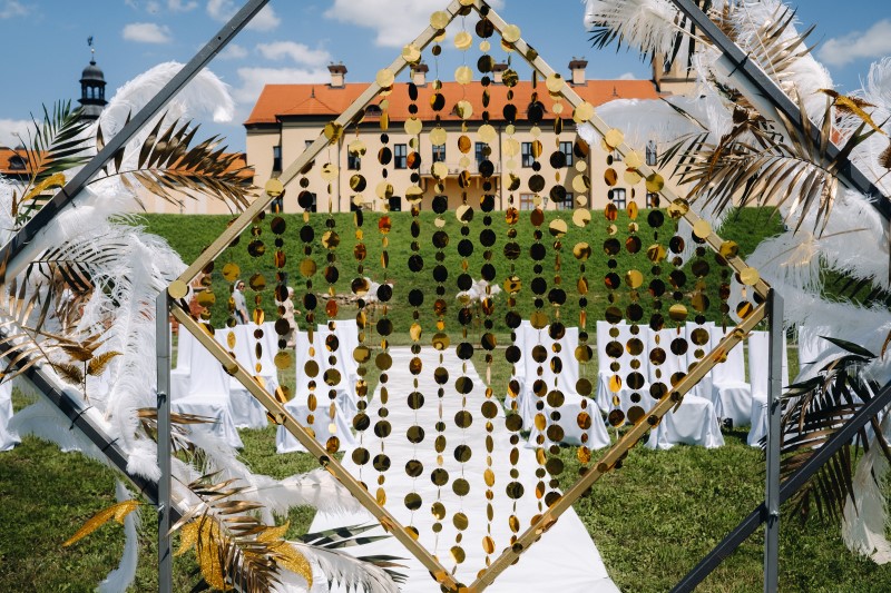 Geschmückter Hochzeitsbogen vor dem Hintergrund einer alten Burg. Hochzeitszeremonie mit einem mit Federn geschmückten Bogen im Retro-Stil.