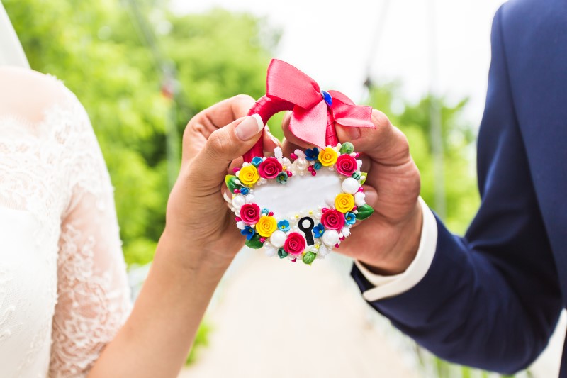 Das Schloss in den Händen der Frischvermählten. Die Hände von Braut und Bräutigam