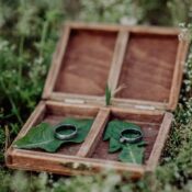 Zwei Eheringe in einer offenen Holzschachtel auf Gras.